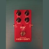 Červený kytarový efekt s nápisy nux, HG-6 a DISTORTION HIGH GAIN. Na horní straně jsou čtyři černé otočné ovířky s popisky LEVEL, GAIN, SCOOP a TONE.…