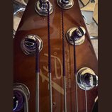 Detail zadní strany hředu kytary v hnědé barvě s kovovými ladicími mechanismy. Na povrchu je vidět zlaté logo a nápisy „Fokus Guitar Shop“ a „Made fo…
