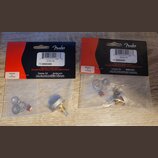 Dvě balená příslušenství značky Fender v plastových sáčcích s červeným a černým kartonem. Na obou je uveden nápis Genuine Fender parts, P.N. 09908340…