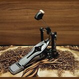 Kovový basový pedál s černým stojanem a stříbrným šlapadlem. Pedál má nastavitelné spojení s pružinou a černý nášlapný mechanismus s bílo-červeným za…