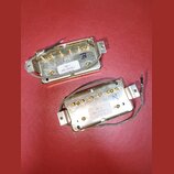 Dvě elektrické kytarové snímače v zlatavém kovovém provedení. Na horním je nálepka s nápisem 498 T, 860-30926-L a datem 01/18/19. Spodní snímač má na…