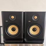 Dva černé studiové monitory značky KRK SYSTEMS. Oba mají žlutý basový reproduktor a menší výškovek v horní části. V dolní části je u obou zařízení ná…