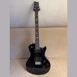 Černá elektrická kytara s dvojstupňovitým tělem a tmavým hmatníkem. Na hlavě je viditelné logo "Epiphone". Hmatník obsahuje bílé vložky ve tvaru pták…