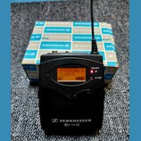 Černý bezdrátový vysílač s displejem, na kterém je text 517.875MHz Y LUDEK01 a indikátor baterie. Na spodní části je bílý nápis SENNHEISER ew 100 G3.…