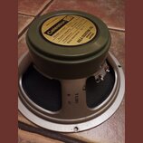 Reproduktor s olivově zeleným magnetem a béžovým rámem. Na horní straně magnetu je žlutá nálepka s nápisy Celestion, Model number G12 H, Power capaci…