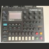 Černý polyfonní digitální syntetizátor s nápisy Polyphonic Digital Synthesizer a Digitone. Na horní straně je bílé logo elektron a osm otočných knofl…