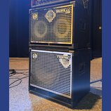 Dvě černé basové reproduktorové skříně naskládané na sebe. Horní skříň má stříbrnou mřížku s nápisy GOLIATH III a 8 OHM a logem značky Warwick. Spodn…