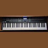 Černý MIDI kontrolér s klaviaturaí. Na levé straně je nápis KEYLAB 61 ESSENTIAL a uprostřed logo ARTURIA. Horní panel obsahuje podsvícené tlačítka, f…