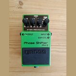 Zelený kytarový efekt s černým spínacím pedálem. Na šasi jsou nápisy Phase Shifter, PH-3 a logo BOSS. Horní panel obsahuje čtyři černé otočné ovladač…