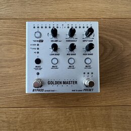 Stříbrný efektový pedál s nápisem GOLDEN MASTER PEDAL a doplňkovým textem 24 BIT 96 KHZ. Zařízení má několik otočných potenciometrů s popisky VU IN O…