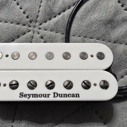 Bílý humbucker s dvěma řadami magnetických pólů. Na spodní části je černým nápisem uveden výrobce Seymour Duncan. Nástroj vykazuje mírné známky opotř…