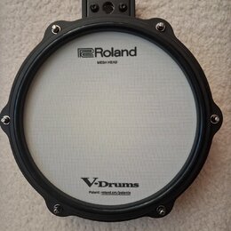 Elektronický buben s bílým mesh povrchem a černým rámem. Na horní části je nápis Roland MESH HEAD a v dolní části V-Drums s doplňkem Patent: roland.c…