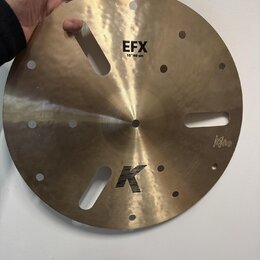 Zlatavý kovový činel s několika otvory různých tvarů a velikostí. Na povrchu jsou čitelné nápisy EFX, 16"/40 cm a logo K. V pravé dolní části je malý…
