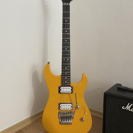 Žlutá elektrická kytara s tmavým hnedým hmatníkem a bílými tečkovanými značkami. Na hlavě je viditelné logo Jackson. Kytara má dva humbuckery, tremol…