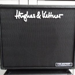 Černý kytarový reproduktor s texturovaným povrchem. V horní části je bílý nápis Hughes & Kettner a v pravém dolním rohu se nachází štítek s nápisem C…