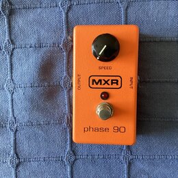 Oranžový kytarový efekt s nápisy OUTPUT a INPUT na bocích. Na horní straně je černý otočný knoflík s nápisem SPEED, logo MXR v černé rámečku a červen…
