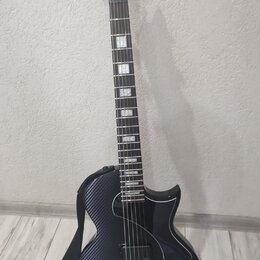 Elektrická kytara s černým povrchem z karbonového vlákna. Na hlavě hmatníku je svisle napsaný bílý nápis "KART". Nástroj má dva humbuckery, jeden ovl…