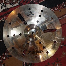 Kovový činel s vryty a otvory v povrchu. Na povrchu je nápis CUSTOM a logo Zildjian. Činely vykazují známky používání v podobě drobných škrábanců a z…