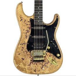 Elektrická kytara s tvarem typu Stratocaster v žluté barvě s výrazným efektem opotřebení a odloupaného laku. Nástroj má černý pickguard, tři snímače…
