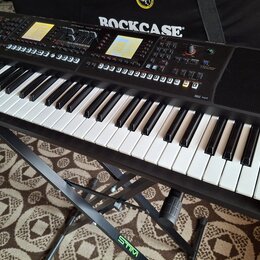 Černý digitální klavír umístěný na černém stojanu s nápisem STIM. Na ovládacím panelu je viditelné logo Roland a nápis XPS-10. Nástroj má bílé a čern…