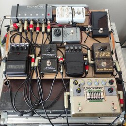 Fotografie zachycuje efektový pedalboard v hliníkovém kufru. Na desce je umístěno několik pedálů s nápisy MORNINGSTAR MIDI CONTROLLED SWITCHER, tc el…
