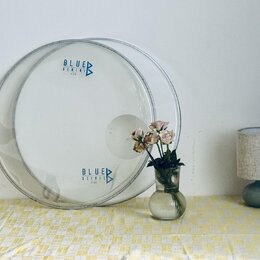 Průhledný plastový buben s nápisy BLUE GEMINI KICK v horní části a BLUE OSIRIS KICK v dolní části, doplněnými o trojúhelníkové logo. Buben je umístěn…