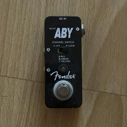 Černý kytarový pedál s nápisy MICRO ABY a Fender. Na horní části je vstup DC IN a přepínač CHANNEL SWITCH s označením A/B ● Y(A&B) a popisem A:RED, B…
