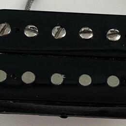 Černý humbucker snímač s dvěma řadami šesti magnetických pólů. Horní řada má viditelné šroubovací hlavy, spodní řada je tvořena hladkými kovovými kol…