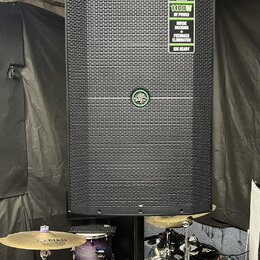 Černý reproduktor s mřížkou, umístěný na stojanu. V pravém horním rohu je zelený štítek s nápisy TRUMP SERIES, 1400W OF POWER, MUSIC DUCKING a FEEDBA…
