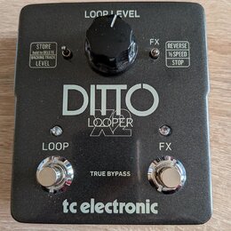 Černý kytarový pedál s nápisy DITTO LOOPER a tc electronic. Horní část obsahuje ovratový knoflík s popiskem LOOP LEVEL a dvě textová pole s funkcemi…
