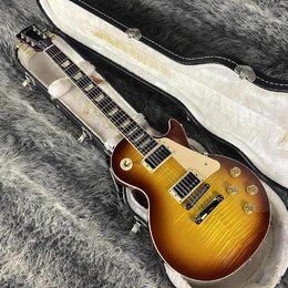 Elektrická kytara s trupem ve tvaru single-cut a barevným přechodem od žluté k tmavě hnědé (sunburst). Nástroj má dva humbuckery, čtyři ovládací knof…