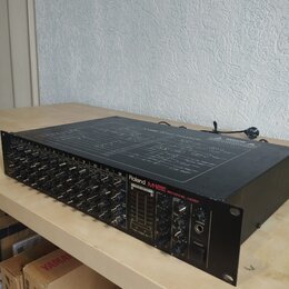 Černý 12kanálový mixážní pult s nápisy Roland M-12E a 12CHANNEL MIXER. Horní kryt obsahuje schéma s názvem M-12E BLOCK DIAGRAM. Zařízení vykazuje mír…