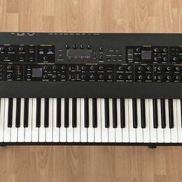 Černý klávesový syntetizátor s bílými a černými klávesami. Na levé straně horního panelu je bílý nápis SEQUENTIAL PROPHET XL a vpravo nápis 8DIO. Pře…