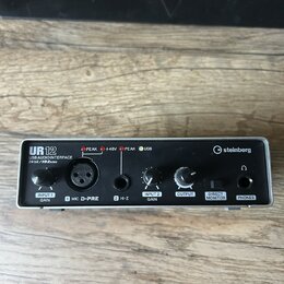 Stříbrné USB audio rozhraní s černými ovládacími prvky a konektory. Na zařízení jsou nápisy UR12, USB AUDIO INTERFACE 24bit/192kHz a logo steinberg.…
