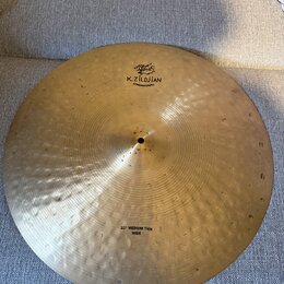 Zlatavý kovový činel s viditelným kovaným povrchem. Na horní části je černý nápis K.ZILDJIAN a pod ním menší text CONSTANTINO PLEI spolu s logem. Ve…