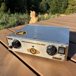 Stříbrný zesilovač v kovovém šasi s dvěma černými oválnými ovladači a zapínacím spínačem. Na předním panelu je nápis Little Mack Vintage Amp 1000, vl…
