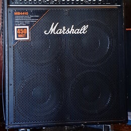 Černý basový kombozesilovač s mřížkou z kovového perforovaného plechu a bílým logem Marshall. V horní části je ovládací panel s knoflíky a nápisy, vč…