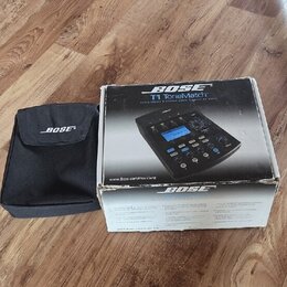Krabice a černý textilní pouzdro s bílým nápisem BOSE. Na krabici je zobrazen přístroj a texty BOSE, T1 ToneMatch, www.bose.com/ToneMatch a BOSE. Kra…