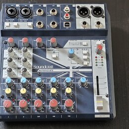Mixážní pult Soundcraft NOTEPAD-BFX v tmavě šedé barvě s kovovými prvky. Na předním panelu jsou vidět různé vstupy, potenciometry a červené tlačítka.…