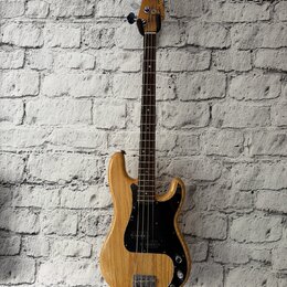 Elektrická basová kytara s přírodním dřevěným povrchem těla a hmatníkem z tmavého dřeva. Na hlavě je nápis "by Heritage Series". Tělo má černý plech…
