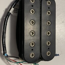 Černý humbucker s dvěma řadami šesti viditelných pólů. Nástroj má plastový kryt a připojovací kabely v červené, bílé, zelené a černé barvě. Povrch pl…