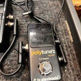 Černý kytarový tuner v kovovém krytu s nápisy polytune 2 noir, true bypass a tc electronic. Povrch zařízení je viditelně poškrábaný a opotřebovaný. K…