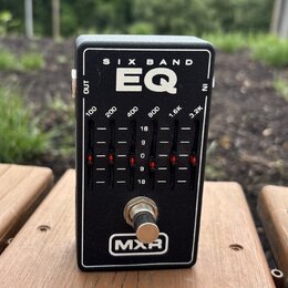 Černý efekt pedál s nápisy SIX BAND a EQ. Na panelu jsou označení frekvencí 100, 200, 400, 800, 1.6K a 3.2K s posuvníky a stupnicí od 18 do 18. V dol…