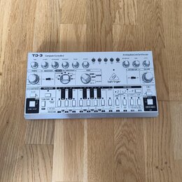 Bílá analogová basová linka syntetizátoru s nápisem TD-3 Computer Controlled Analog Bass Line Synthesizer a logem behringer. Zařízení obsahuje řadu o…