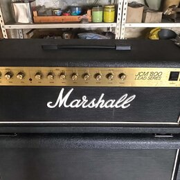 Černý kytarový zesilovač s nápisem Marshall a označením JCM 800 LEAD SERIES na zlatém předním panelu. Panel obsahuje řadu ovládacích knoflíků a přepí…