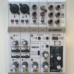 Bílá mixovací konzole Yamaha AG06. Na horním panelu jsou vstupy XLR, jacky a konektory RCA s nápisy L/MONO, R, L, R, STEREO OUT a MONITOR OUT. Přední…