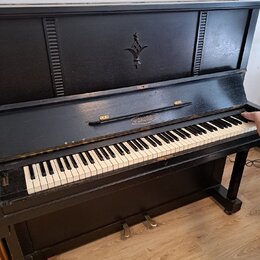 Černé akustické piano s klaviaturou z bílých a černých kláves. Na přední části nad klaviaturou je nápis AKORD v oválném rámečku a v horní části korpu…