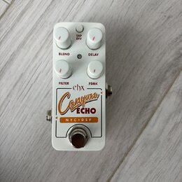 Bílý efekt pedál s nápisy ehx, Canyon ECHO a NYC DSP. Pedál má čtyři bílé otočné ovladače s popisky BLEND, DELAY, FILTER a FDBK a jedno tlačítko TAP…