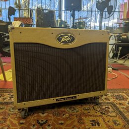 Kytarový kombo zesilovač v béžovém potahu s texturou. Na horní části je oválné logo Peavey a v dolní části nápis Peavey Classic 50. Přední strana je…