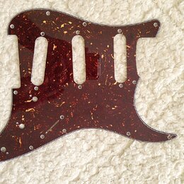 Tmavě červený pickguard s texturou želvy (tortoise shell) určený pro elektrickou kytaru. Má tři vyřezané otvory pro snímače a několik otvorů pro šrou…